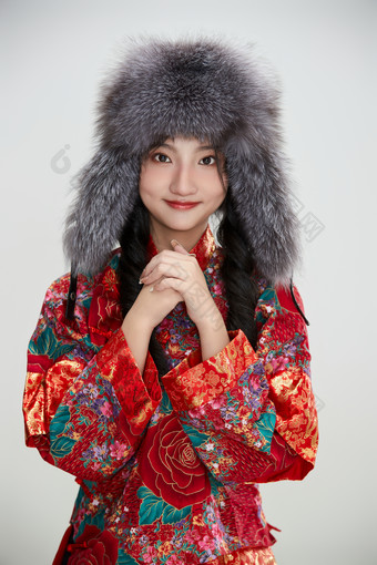 白色背景下穿中国传统<strong>服</strong>饰头戴绒帽的少女