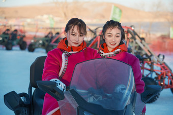 在冰天雪地玩耍雪上娱乐载具车辆的闺蜜少女