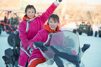 在冰天雪地玩耍雪上娱乐载具车辆的闺蜜少女