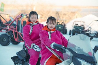 在冰天雪地玩耍雪上娱乐载具车辆的闺蜜少女