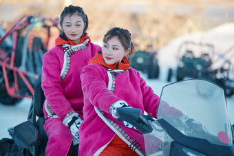 在冰天雪地玩耍雪上娱乐载具车辆的闺蜜少女