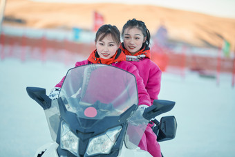 在冰天雪地玩耍雪上娱乐载具车辆的闺蜜少女