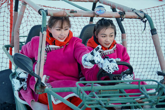 在冰天雪地玩耍雪上娱乐载具车辆的<strong>闺蜜</strong>少女