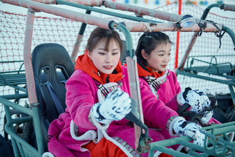 在冰天雪地玩耍雪上娱乐载具车辆的闺蜜少女