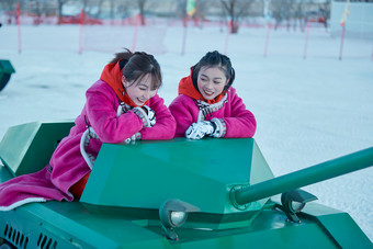 在冰天雪地玩耍雪上娱乐载具车辆的闺蜜少女