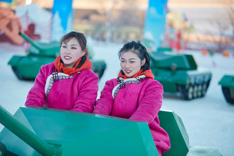 在冰天雪地玩耍雪上娱乐载具车辆的闺蜜少女