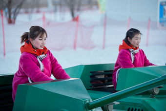 在冰天雪地玩耍雪上娱乐载具车辆的闺蜜少女