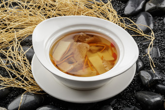 白色汤盆装的至尊菌皇汤摆放在黑色鹅卵石上