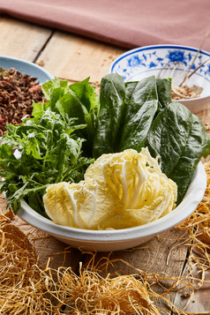 白色瓷盆装的火锅涮菜茼蒿白菜菠菜