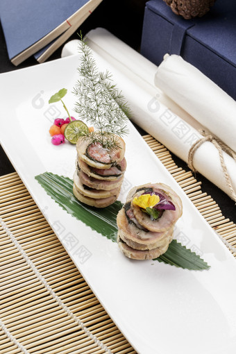 长方形瓷盘装的猪肉海苔香肠卷摆放在寿司帘上