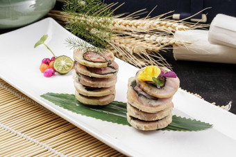 长方形瓷盘装的猪肉海苔香肠卷摆放在寿司帘上