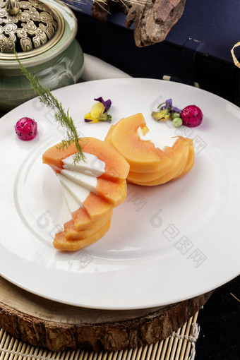 白色圆瓷盘装的木瓜蛋白摆放在樟木砧板上