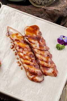 米花色瓷盘装的蜜汁叉烧肉摆放在樟木砧板上