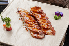 米花色瓷盘装的蜜汁叉烧肉摆放在樟木砧板上