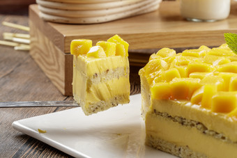 芒果奶油三层蛋糕摆放在木纹底板上