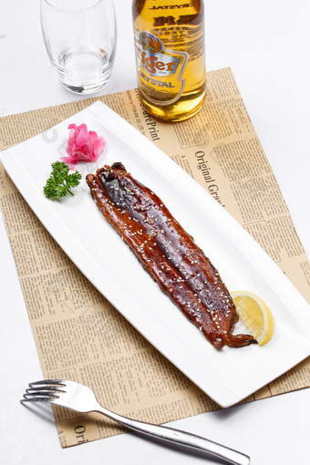 长方形瓷盘装的日式烤鳗鱼摆放在英文包装纸上