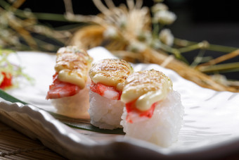 芝士焗蟹钳肉手握寿司摆放在寿司帘上图片