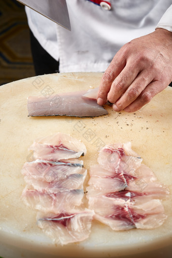 白色砧板上厨师用精湛的刀工展示生鱼片及鲜鱼料理切割分切的刀工