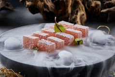 干冰缭绕的黑瓷餐具摆放的番茄糖霜江米糕
