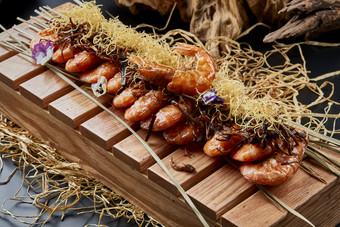 木质餐具上摆放的薯丝梅菜焗大明虾