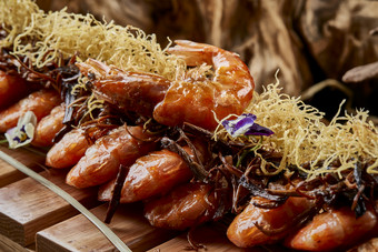 木质餐具上摆放的薯丝梅菜焗大明虾