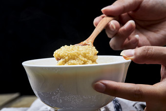 手持木勺㧟起的美味香浓小米粥