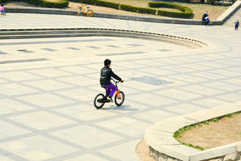 春天公园广场上骑单车的男孩