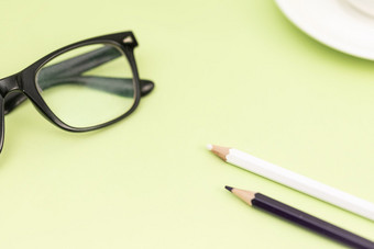 绿色背景上的铅笔与眼镜