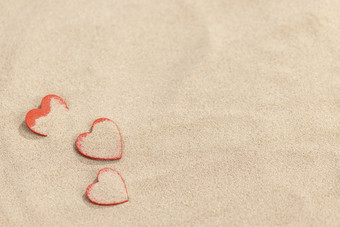 夏日沙滩上的三颗红色爱心