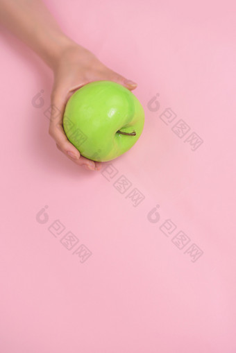 手拿绿苹果粉色背景