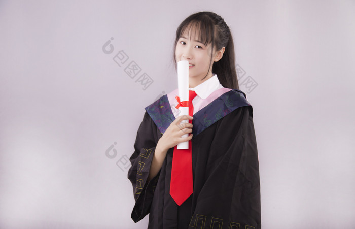 纯色背景下穿着学士服的女孩