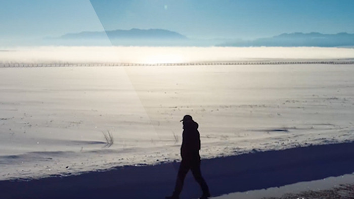 赛里木湖雪景中一个人在公路上行走