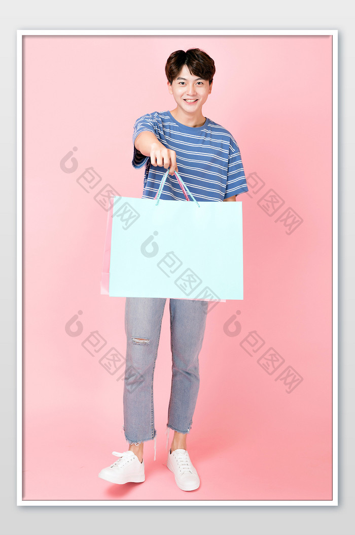手提购物袋微笑的年轻男性人像图片