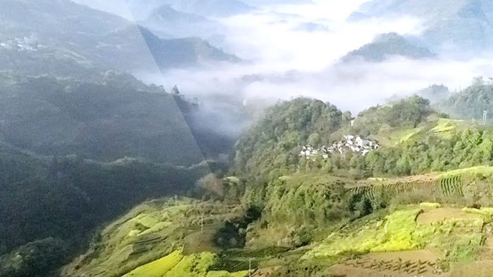 航拍俯瞰小村庄徽派建筑环绕云雾黄山