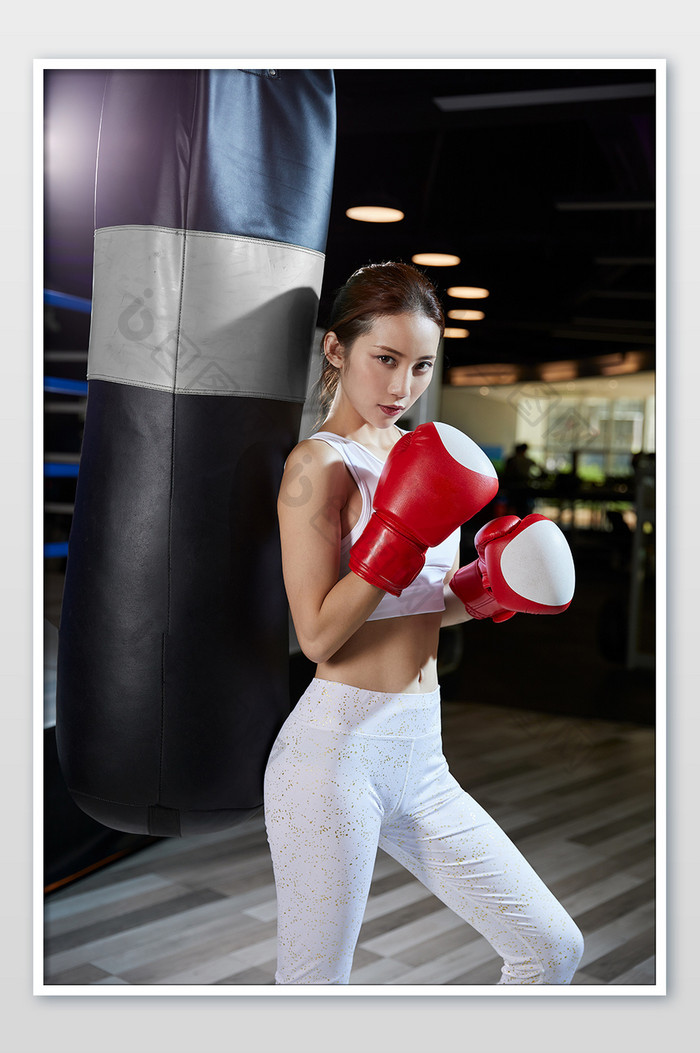 健身房运动女生靠沙包帅气拳击姿势宣传图