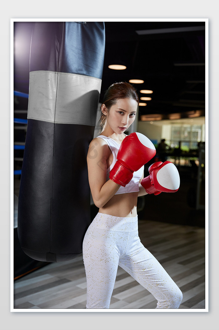 健身房运动女生靠沙包帅气拳击姿势宣传图图片