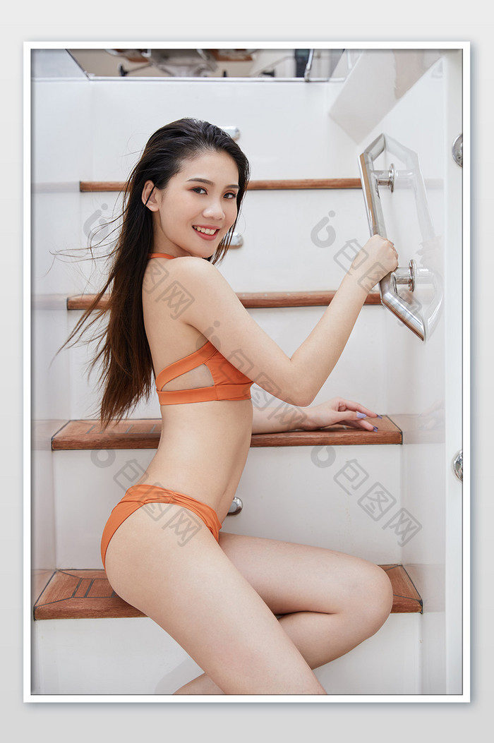 夏天海滨游艇侧身坐在楼梯上的比基尼美女