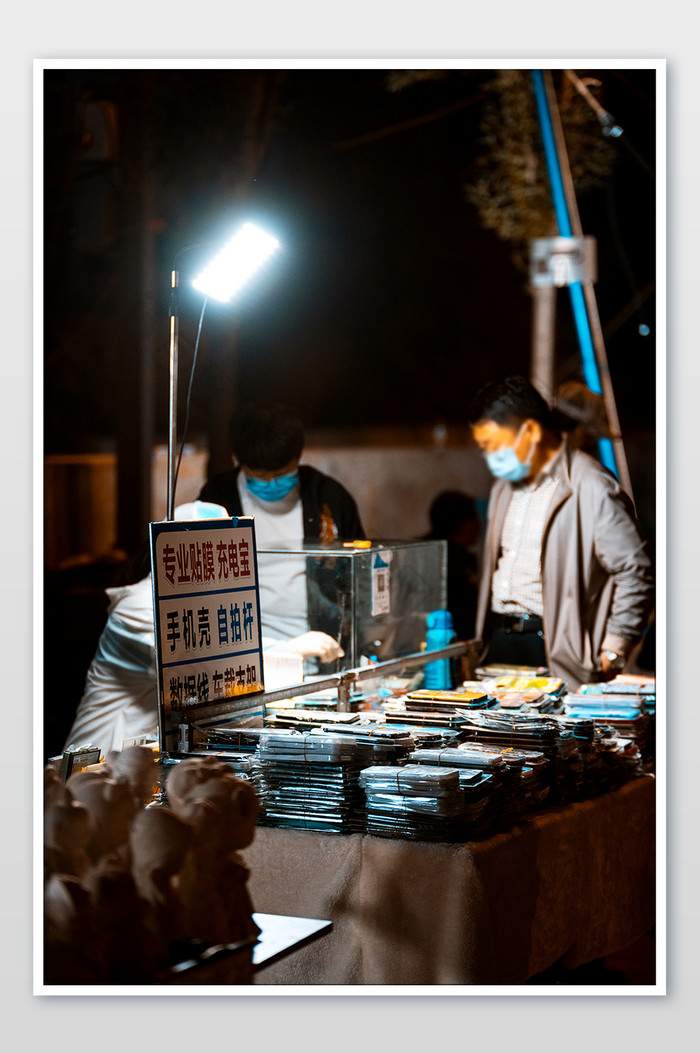 夜市晚间在贴膜摊位等待的路人图片图片