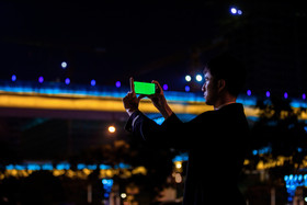 西装男手机拍摄绿屏画面夜景