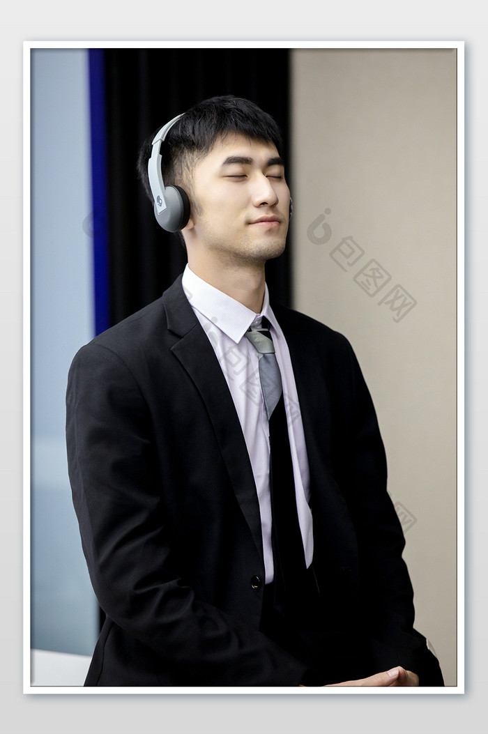 商务西装年轻男带耳机享受音乐摄影图