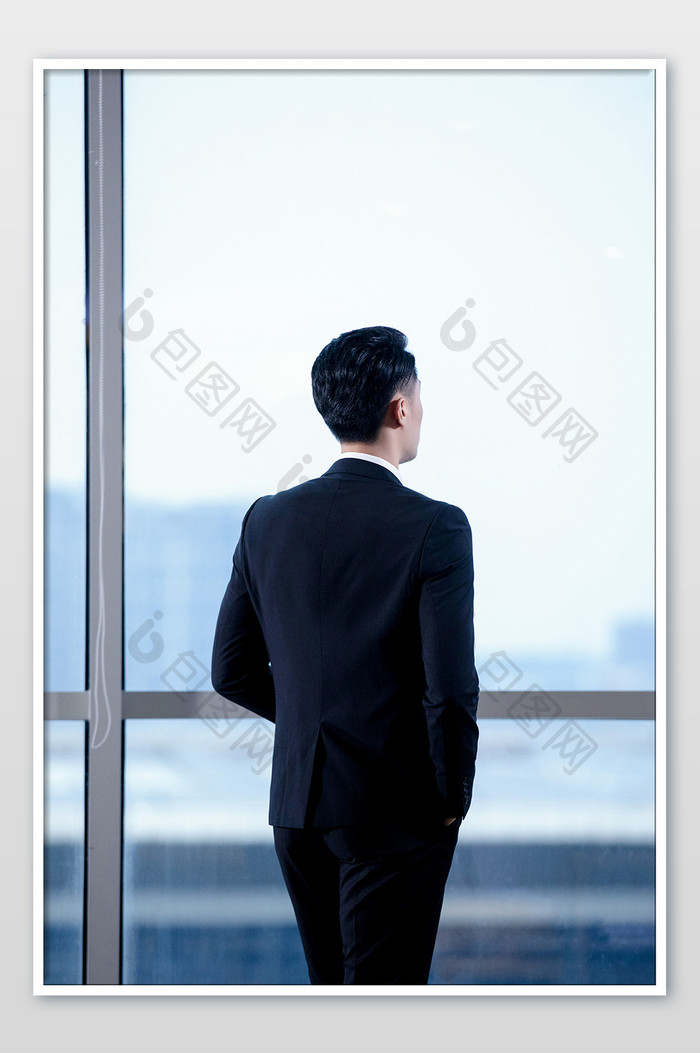 商务窗边西装男背影看向窗外摄影图