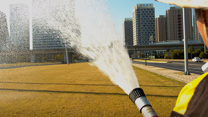 4K实拍在草坪上洒水的环卫工人视频素材