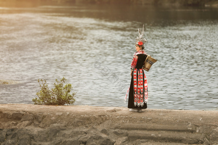 背着背篓的苗族姑娘在河边图片