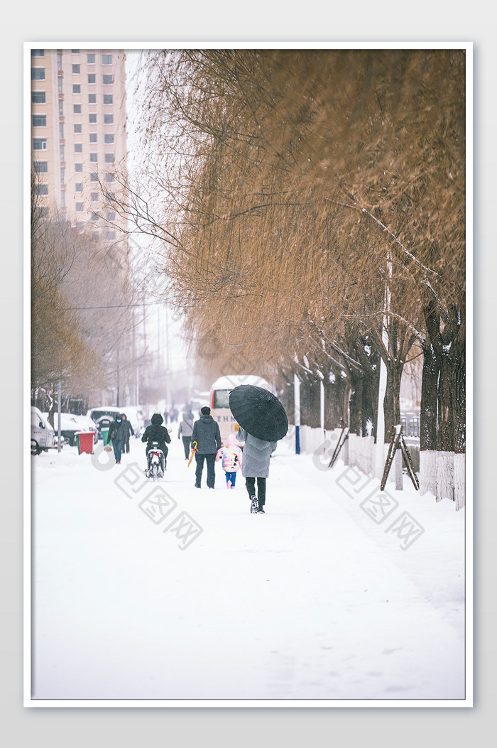 冬天大雪过后打伞行走的路人摄影图