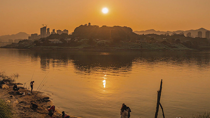 夕阳下江边钓鱼玩耍的人们日落延时