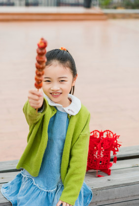 红色喜庆女童拿糖葫芦摄影图片