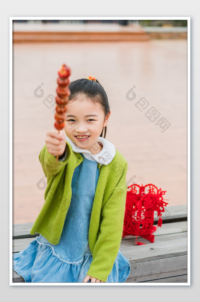 红色喜庆女童拿糖葫芦摄影图片