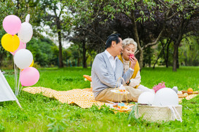 清新老年夫妇野外露营喂苹果摄影照片