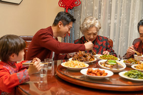 新年家人团圆饭相互夹菜摄影图片