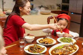 新年妈妈给女儿夹团员菜摄影图片